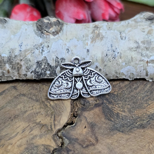 Das Bild zeigt einen Anhänger der auf der Vorderseite ein Reliefmuster der Mondzyklen hat und auf der anderen Seite glatt ist. Oben hat er eine feste Öse. Er ist ideal für die individuelle Schmuckherstellung.