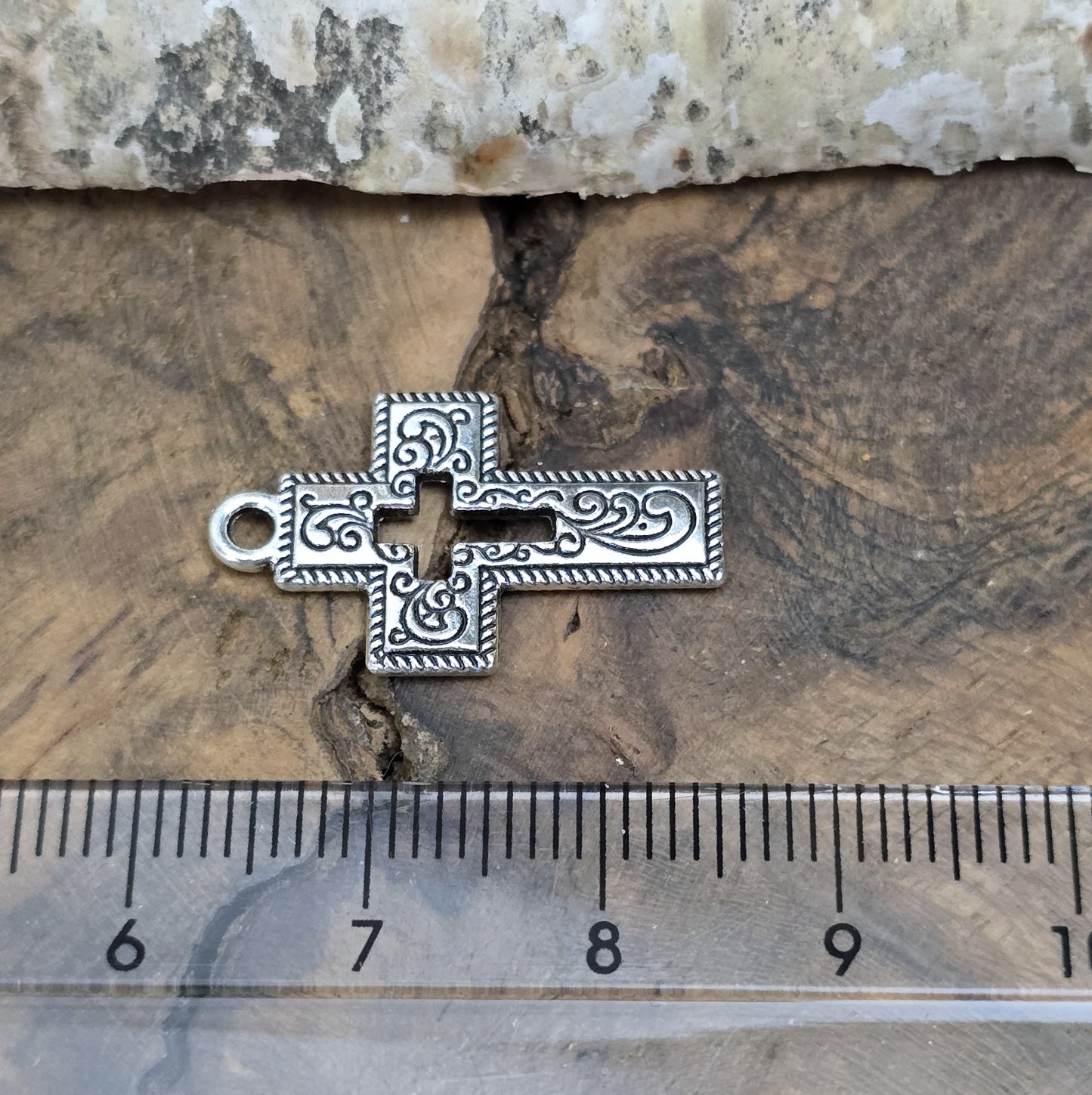 Das Bild zeigt einen charmanten Kreuz-Anhänger in antik silberfarbiger Ausführung. Mit einer Größe von 23 mm sind sie ideal für Ihre individuelle Schmuckherstellung.