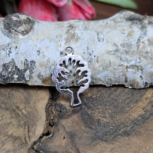 Das Bild zeigt einen Anhänger in Form eines Baums in antik silberfarbig mit der Silhouette eines Baum in der Mitte. Ideale Schmuckkomponenten für Ohrringe und Armbänder.