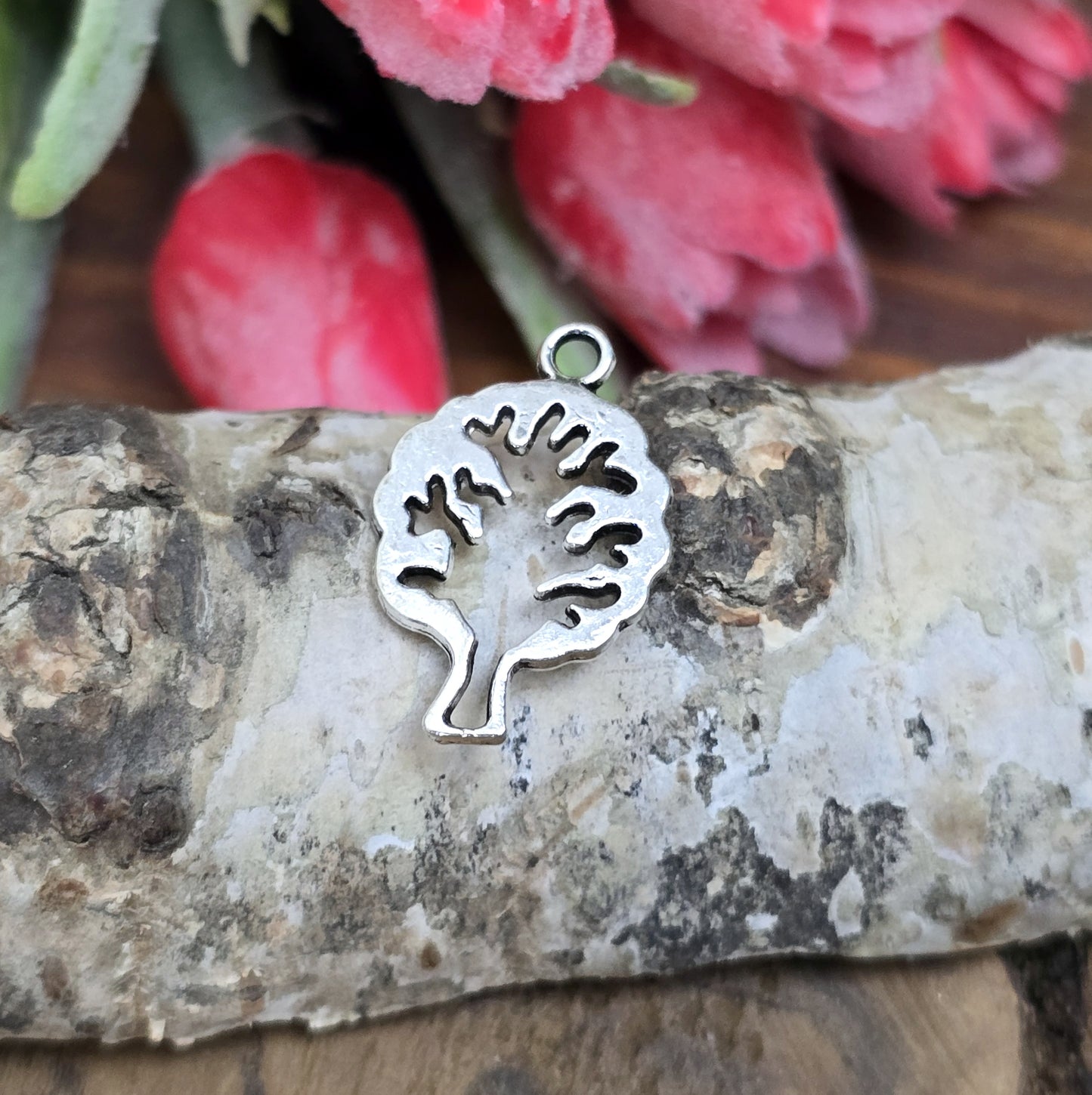 Das Bild zeigt einen Anhänger in Form eines Baums in antik silberfarbig mit der Silhouette eines Baum in der Mitte. Ideale Schmuckkomponenten für Ohrringe und Armbänder.