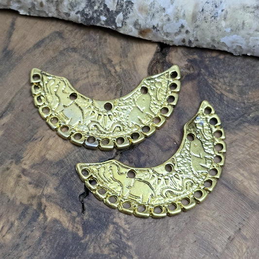 2 einzigartige, halbrunde Multiverbinder im Bollywood-Stil. Die ideale Schmuckkomponente für Tiaras, Fußschmuck, Handketten und Ohrschmuck im beliebt indischen Bollywood-Design. Die Verbinder sind antik silberfarbig und verfügen im inneren Bogen über 3 Löcher und am unteren Außenbogen befinden sich 17 Löcher. Auf dem Bogen selbst sind 2 Elefanten abgebildet sowie eine Sonne.