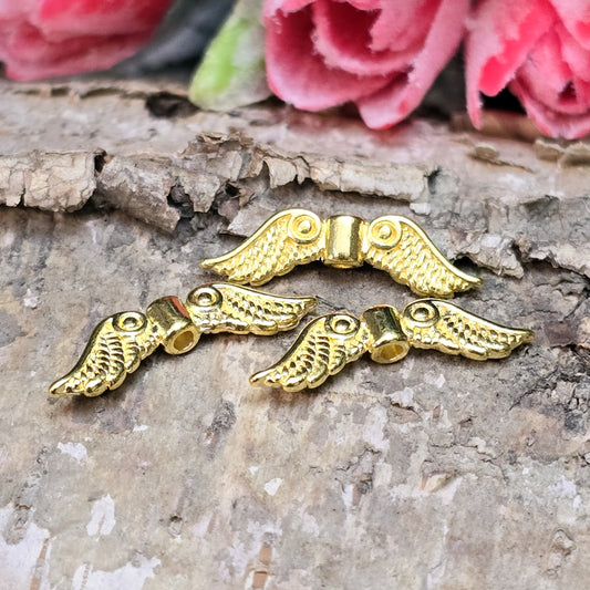 Auf dem Bild sind vergoldete Metallperlen in Form von Engelsflügeln zu sehen. Mit einer Größe von 22 mm eignen sie sich ideal für die Herstellung von Schmuckstücken wie Schutzengeln und anderen kreativen DIY-Projekten.