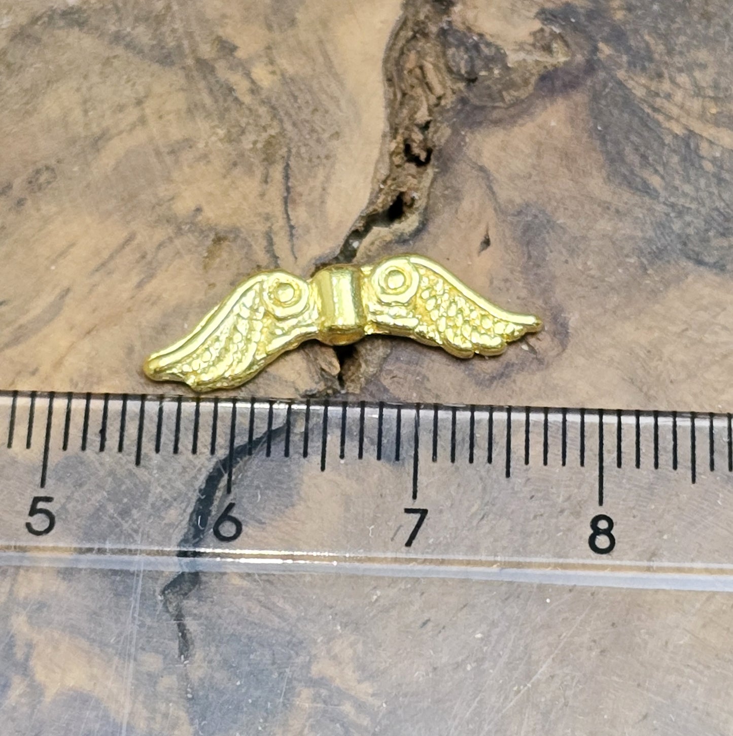 Auf dem Bild sind vergoldete Metallperlen in Form von Engelsflügeln zu sehen. Mit einer Größe von 22 mm eignen sie sich ideal für die Herstellung von Schmuckstücken wie Schutzengeln und anderen kreativen DIY-Projekten.