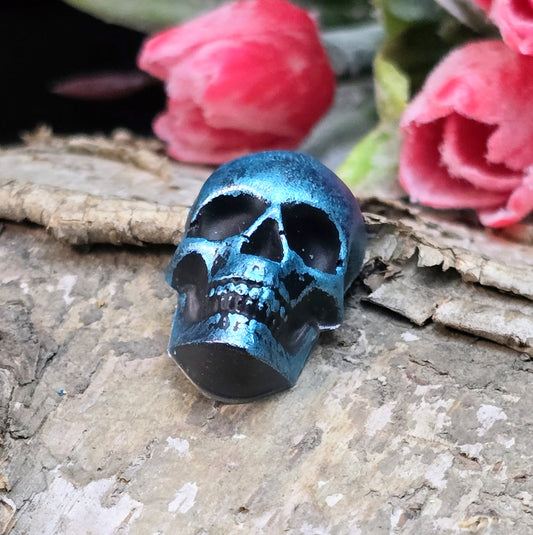 Das Bild zeigt einen Totenkopf-Cabochon in Schwarz mit türkisfarbener Wachsverzierung