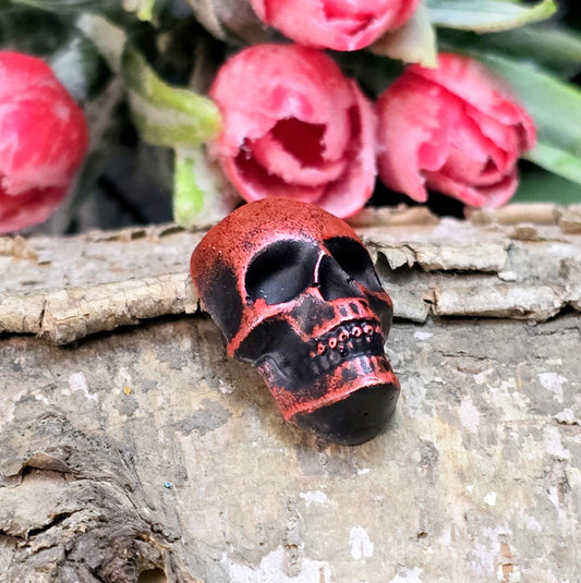 Das Bild zeigt einen Totenkopf-Cabochon in Schwarz mit roter Wachsverzierung