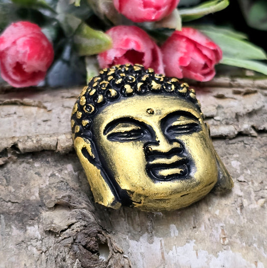 Auf dem Bild ist ein handgefertigter Buddhakopf aus Kunstharz zu sehen. Der Kopf ist mit feinen, handbemalten Details verziert und hat eine flache Rückseite, die ideal für die Schmuckherstellung oder Bastelprojekte geeignet ist.