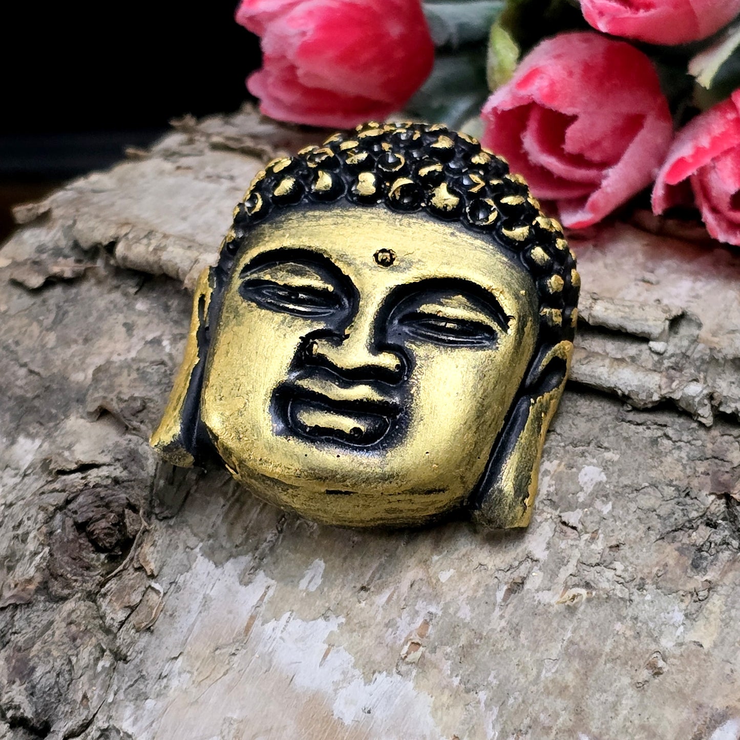 Auf dem Bild ist ein handgefertigter Buddhakopf aus Kunstharz zu sehen. Der Kopf ist mit feinen, handbemalten Details verziert und hat eine flache Rückseite, die ideal für die Schmuckherstellung oder Bastelprojekte geeignet ist.