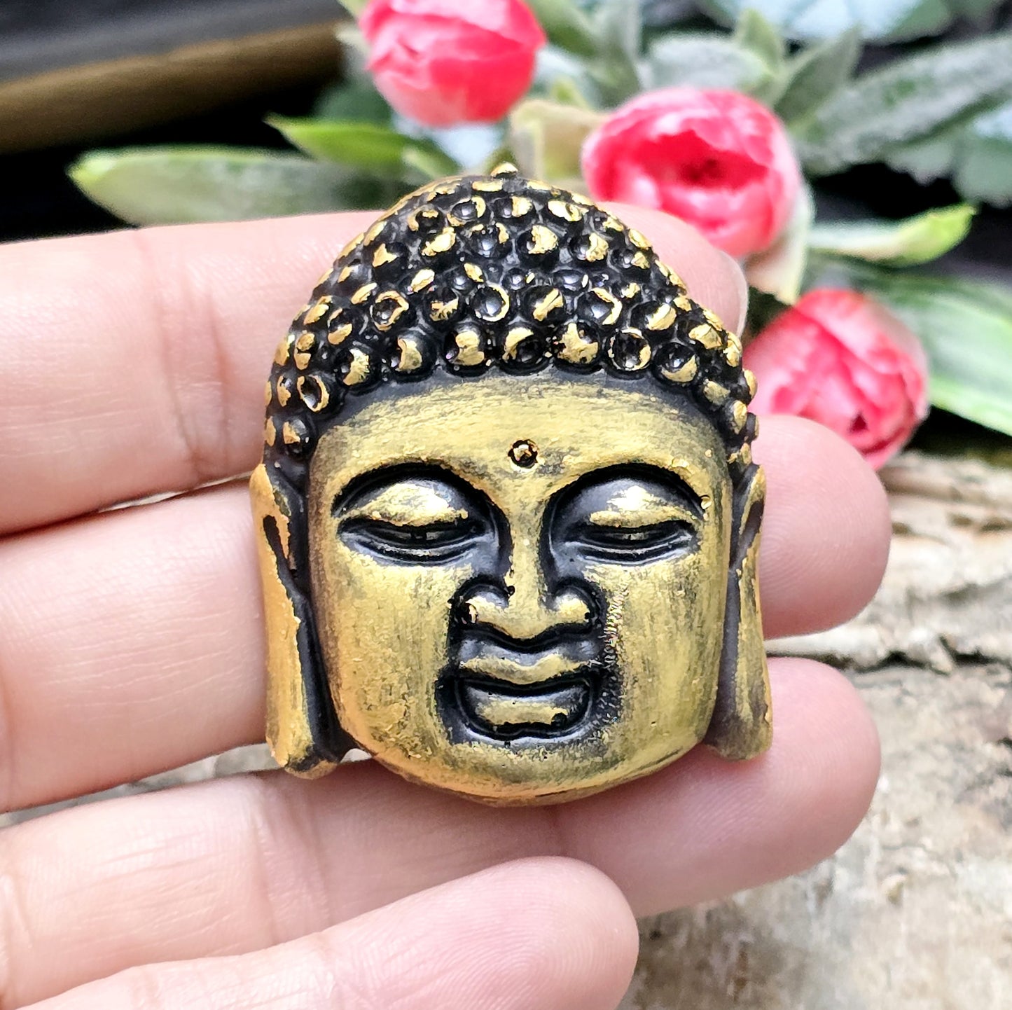 Auf dem Bild ist ein handgefertigter Buddhakopf aus Kunstharz zu sehen. Der Kopf ist mit feinen, handbemalten Details verziert und hat eine flache Rückseite, die ideal für die Schmuckherstellung oder Bastelprojekte geeignet ist.