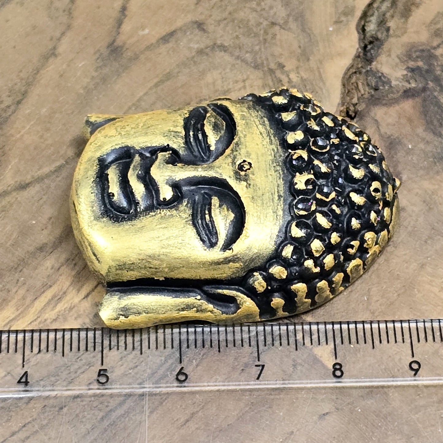 Auf dem Bild ist ein handgefertigter Buddhakopf aus Kunstharz zu sehen. Der Kopf ist mit feinen, handbemalten Details verziert und hat eine flache Rückseite, die ideal für die Schmuckherstellung oder Bastelprojekte geeignet ist.