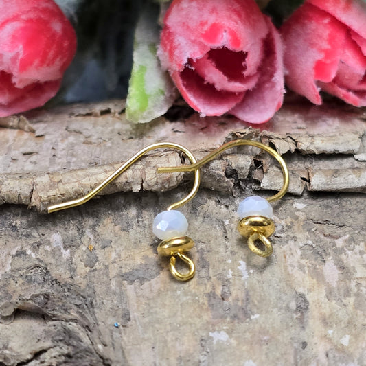 Das Bild zeigt ein paar handgefertigte Ohrhaken mit weißer Kristallglasperle, um ein paar Ohrringe herzustellen