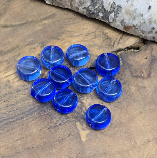 Das Bild zeigt, blaue, transparente Glasperlen in Münzform. Ideal zur individuellen Schmuckherstellung.