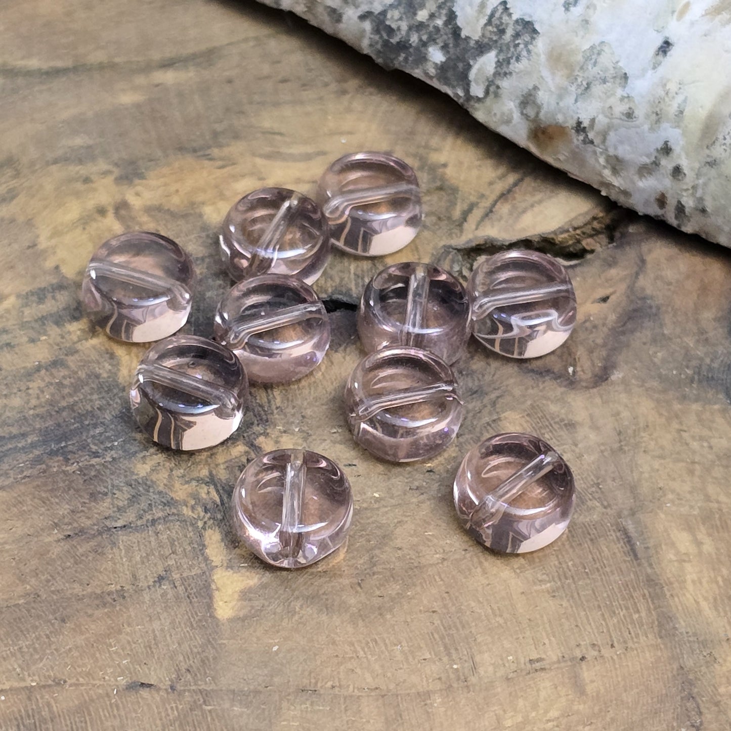 Das Bild zeigt kleine münzförmige Glasperlen in der Farbe Amethyst, für die individuelle Schmuckherstellung.