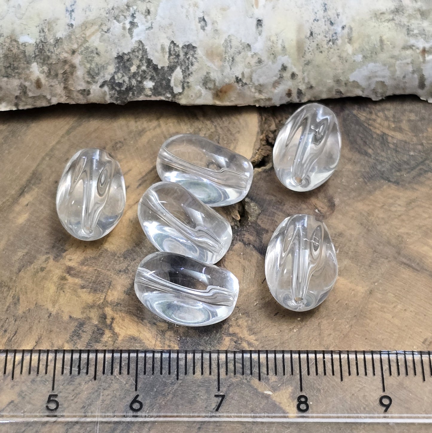Das Bild zeigt Glasperlen in Nuggetform, farblos transparent. 13mm