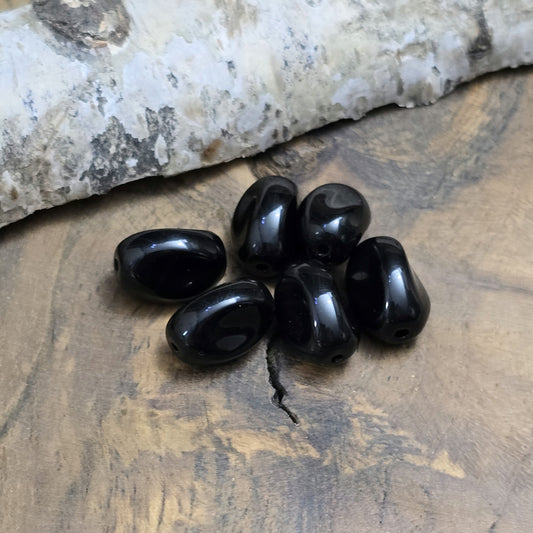 Das Bild zeigt 12 opak schwarze Glasperlen in Nuggetform – 13mm – Für deinen eleganten Schmuck