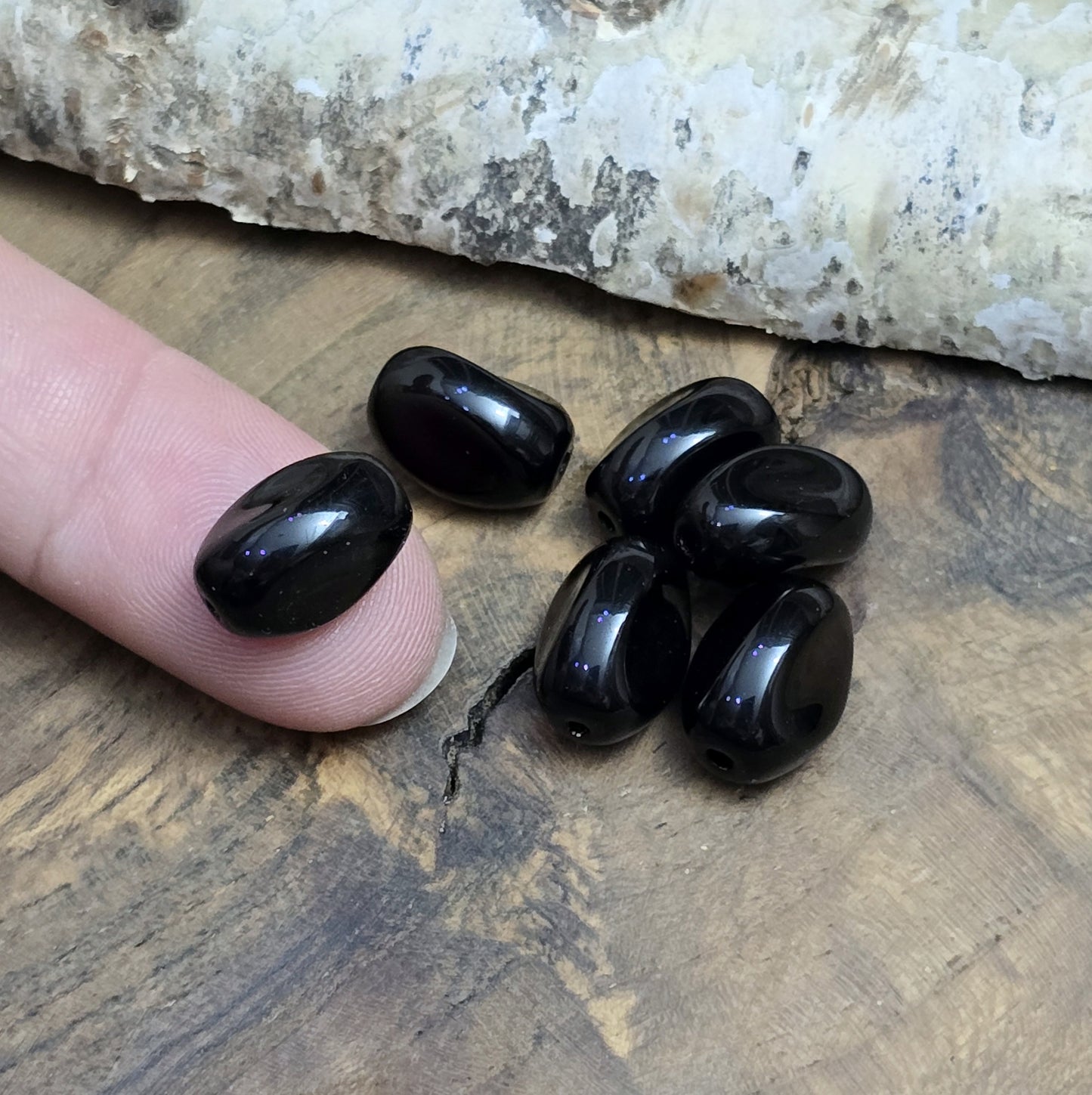 Das Bild zeigt 12 opak schwarze Glasperlen in Nuggetform – 13mm – Für deinen eleganten Schmuck