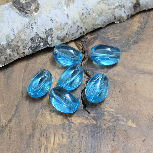 Das Bild zeigt 12 transparente Glasperlen in Nuggetform – Aquablau – 13mm – Für strahlend frische Schmuckkreationen