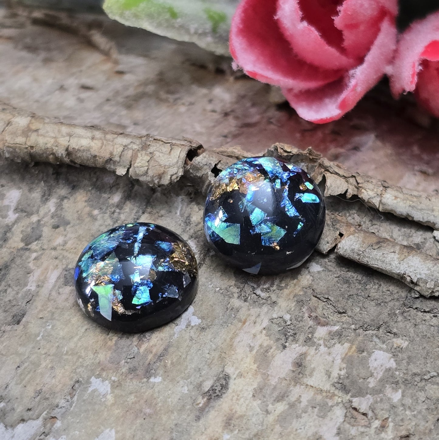 Das Bild zeigt vier runde Cabochons mit einem Durchmesser von 12 mm. Sie sind tiefschwarz und haben eine glatte, glänzende Oberfläche. Im Inneren der Cabochons befinden sich feine, schimmernde Flakes, die je nach Lichteinfall dezent funkeln. Die Flakes erzeugen kleine, reflektierende Lichtpunkte, die dem Schwarz eine besondere Tiefe verleihen. Die Cabochons wirken edel und modern. Sie eignen sich für die Schmuckherstellung, beispielsweise für Ringe, Anhänger oder Ohrstecker.