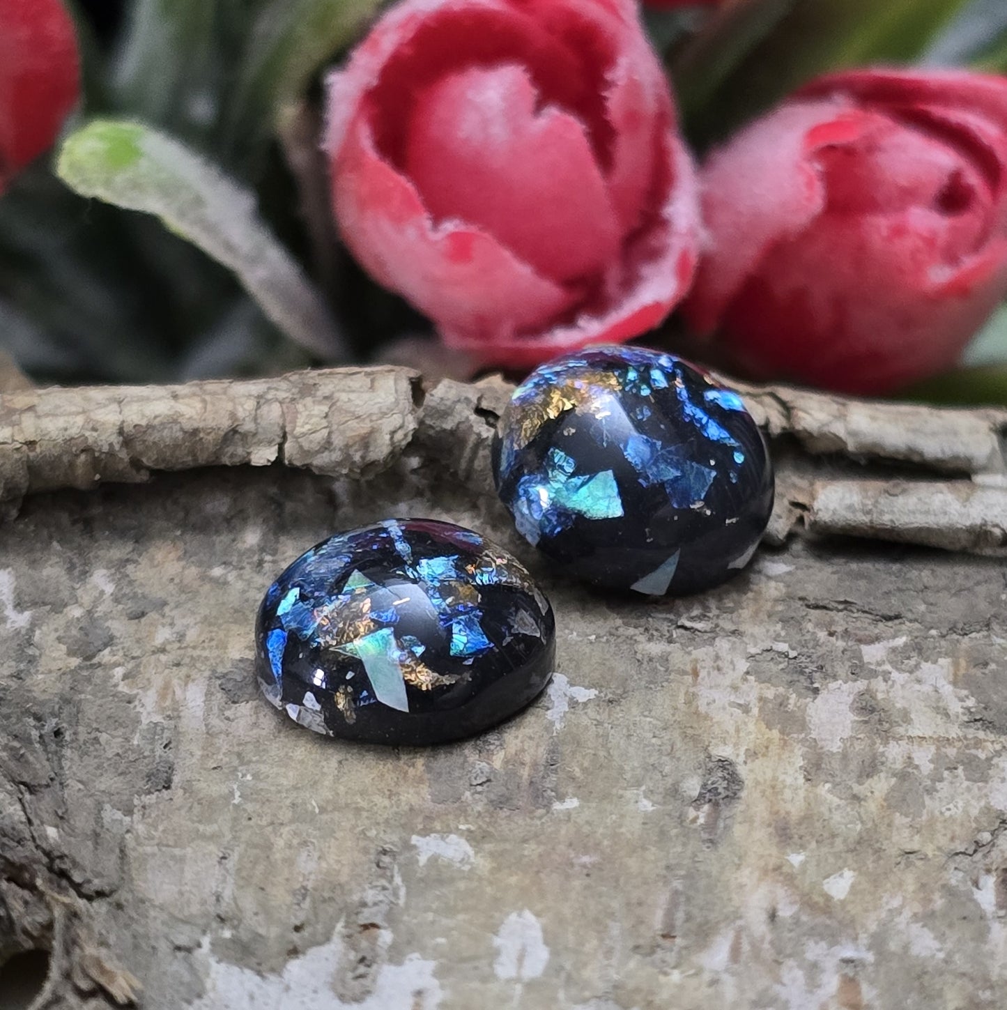 Das Bild zeigt vier runde Cabochons mit einem Durchmesser von 12 mm. Sie sind tiefschwarz und haben eine glatte, glänzende Oberfläche. Im Inneren der Cabochons befinden sich feine, schimmernde Flakes, die je nach Lichteinfall dezent funkeln. Die Flakes erzeugen kleine, reflektierende Lichtpunkte, die dem Schwarz eine besondere Tiefe verleihen. Die Cabochons wirken edel und modern. Sie eignen sich für die Schmuckherstellung, beispielsweise für Ringe, Anhänger oder Ohrstecker.