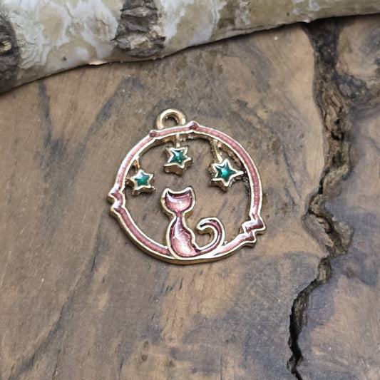 Der goldfarbene Anhänger zeigt eine funkelnde rotfarbene Katze, die von leuchtenden grünen Sternen umgeben ist. Die elegante Umrandung hebt das Design hervor und verleiht ihm eine zauberhafte Ausstrahlung. Mit einer Größe von 21 mm eignet sich der Anhänger perfekt für die Schmuckherstellung oder kreative DIY-Projekte.