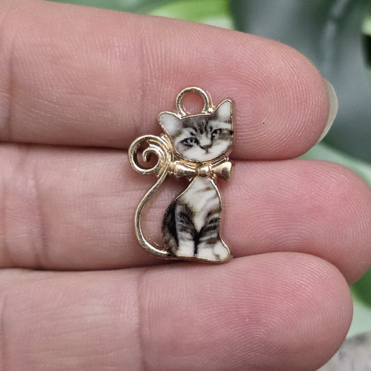 Das Bild zeigt einen goldfarbenen Anhänger in Form einer getigerten Katze. Die Katze ist detailliert gestaltet, mit einem markanten Tiger-Muster auf ihrem Fell, das dem Anhänger eine kraftvolle Ausstrahlung verleiht. Der Anhänger hat eine glänzende goldfarbene Umrandung, die das Design elegant hervorhebt. Mit einer Größe von ca. 21mm eignet sich der Anhänger perfekt für Schmuckkreationen oder kreative DIY-Projekte.