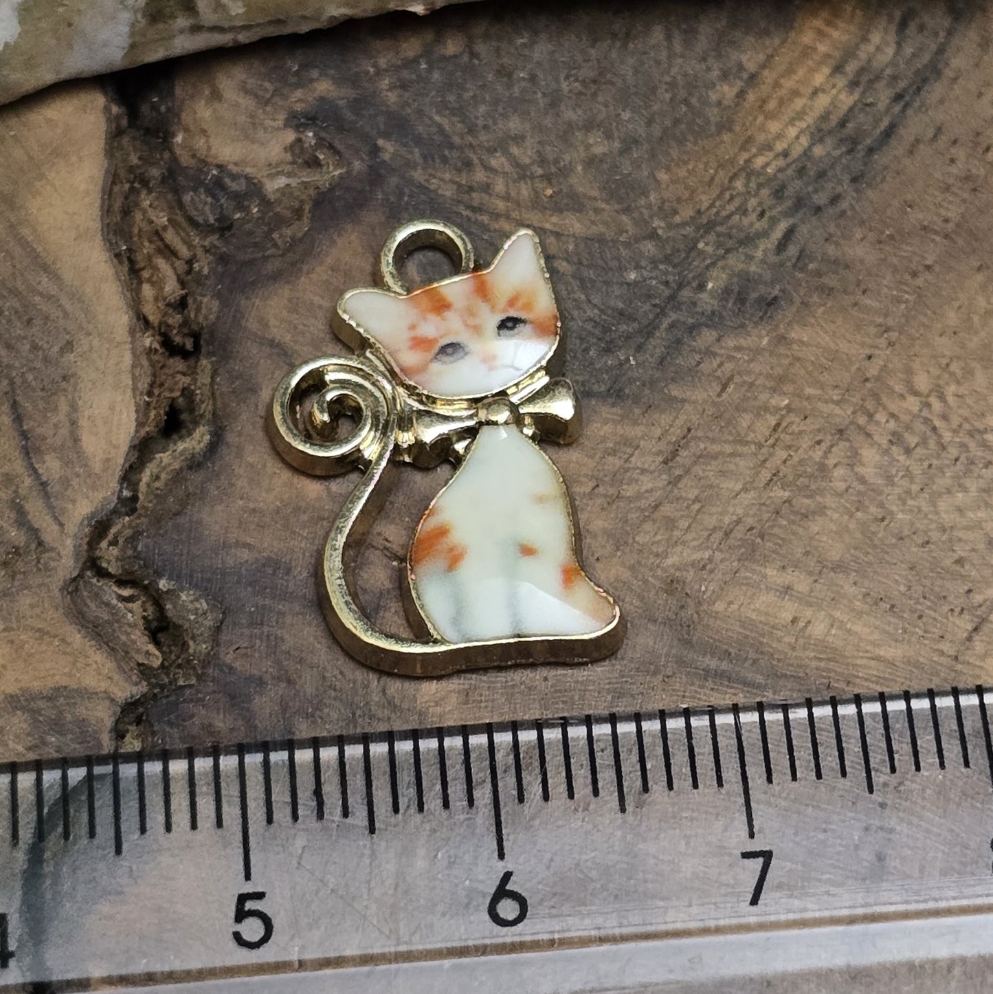 Das Bild zeigt einen goldfarbenen Anhänger mit einer rot getigerten Katze. Die Katze ist detailliert mit einem auffälligen rot-getigerten Fellmuster dargestellt, das dem Anhänger eine lebendige und energiegeladene Ausstrahlung verleiht. Der Anhänger hat eine elegante goldfarbene Umrandung, die das Design zusätzlich betont. Mit einer Größe von ca. 21mm eignet sich der Anhänger perfekt für Schmuckkreationen oder kreative DIY-Projekte.