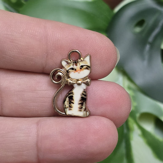 Das Bild zeigt einen goldfarbenen Anhänger mit einer braun getigerten Katze. Das braune Tigermuster auf der Katze verleiht dem Anhänger eine natürliche, warme Ausstrahlung. Die goldfarbene Umrandung betont das Design und sorgt für einen eleganten Touch. Der Anhänger hat eine Größe von ca. 21mm und eignet sich hervorragend für Schmuckkreationen oder DIY-Projekte.