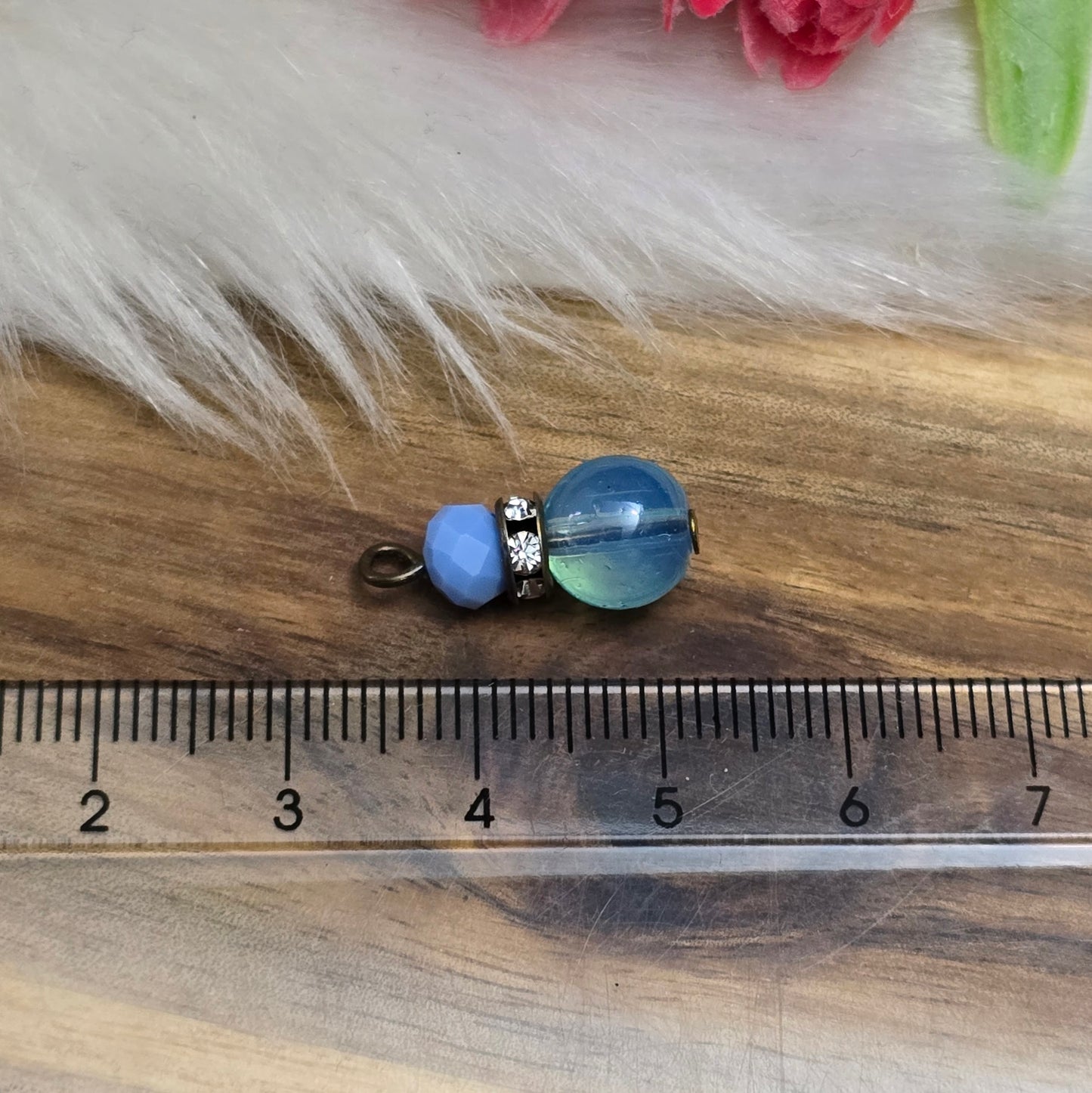 Das Bild zeigt zwei handgefertigte Anhänger mit einer Kombination aus transparenten hellblauen Glasperlen und opaken hellblauen Kristallglasperlen. Ein funkelndes Strassrondell setzt glitzernde Akzente, während antik bronzefarbige Metallelemente dem Design einen charmanten Vintage-Touch verleihen. Die filigranen Details und die harmonische Farbzusammenstellung machen die Anhänger zu einem stilvollen Blickfang für Schmuckkreationen.