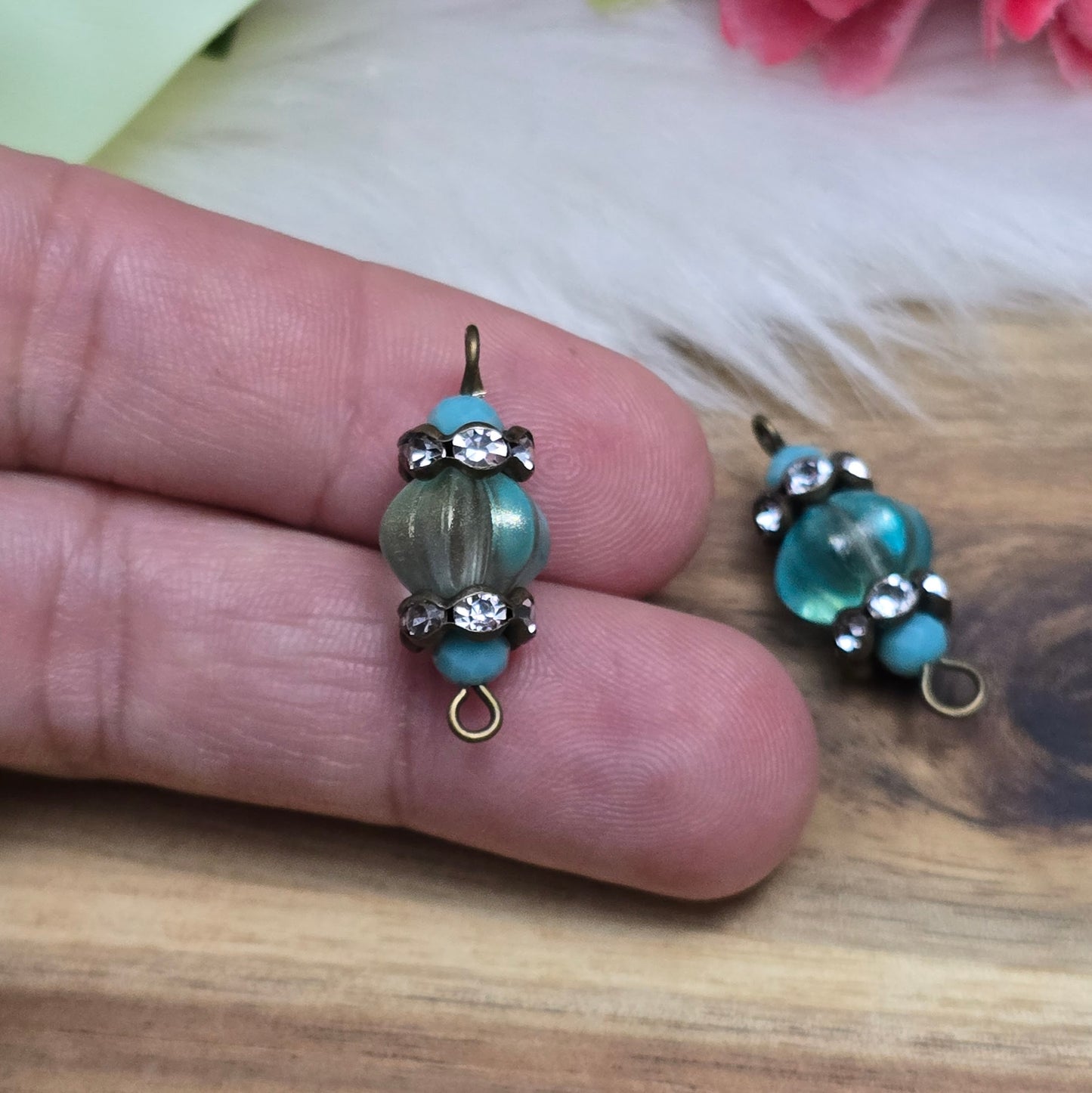 Das Bild zeigt zwei handgefertigte Verbinder mit mintfarbenen Glasperlen in Kürbisform und facettierten Kristallglasperlen. Strassrondelle sorgen für funkelnde Akzente, während antik bronzefarbene Metallelemente dem Design einen eleganten Vintage-Charme verleihen. Die Verbinder sind ca. 25mm groß und ideal für Schmuckkreationen.