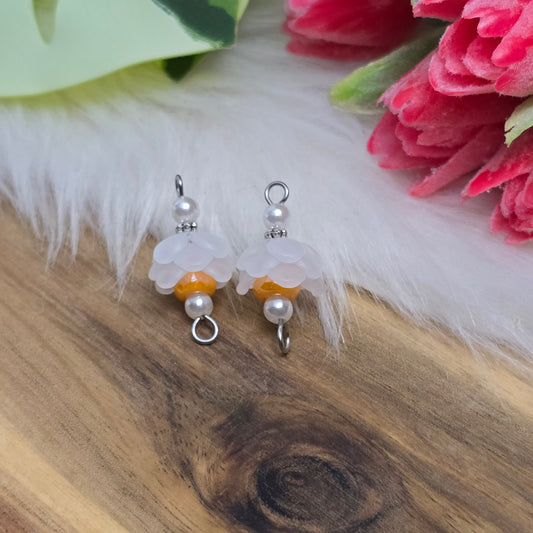 Auf dem Bild sind zwei handgefertigte Blütenverbinder zu sehen. Diese bestehen aus mattierten, weißen Acrylblütenkäppchen, die harmonisch mit cremefarbenen Acrylperlen und leuchtenden, orangen böhmischen Glasperlen kombiniert sind. Die Verbinder haben eine Länge von ca. 24mm und eine Breite von 12mm. Sie sind ideal für kreative Schmuckprojekte und verleihen Armbändern, Halsketten und Ohrringen einen frischen, romantischen Look.