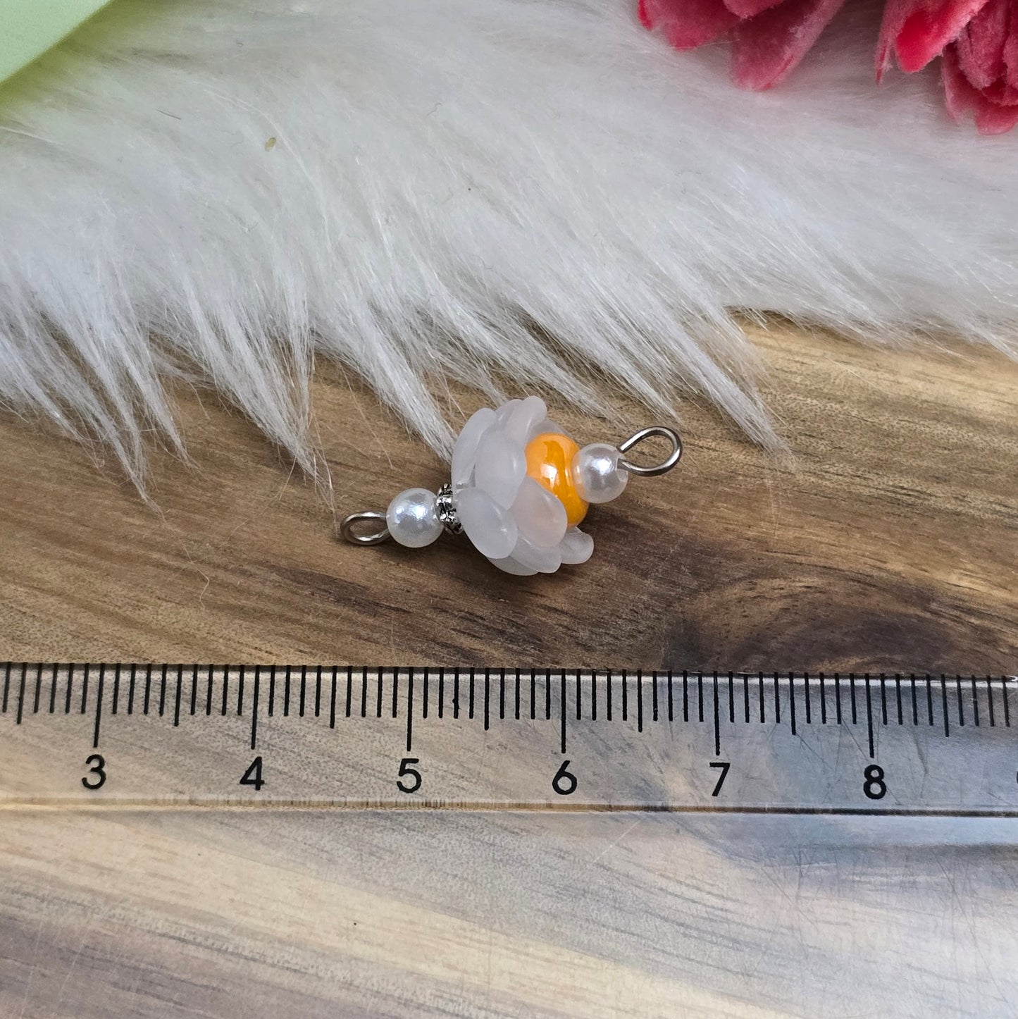 Auf dem Bild sind zwei handgefertigte Blütenverbinder zu sehen. Diese bestehen aus mattierten, weißen Acrylblütenkäppchen, die harmonisch mit cremefarbenen Acrylperlen und leuchtenden, orangen böhmischen Glasperlen kombiniert sind. Die Verbinder haben eine Länge von ca. 24mm und eine Breite von 12mm. Sie sind ideal für kreative Schmuckprojekte und verleihen Armbändern, Halsketten und Ohrringen einen frischen, romantischen Look.
