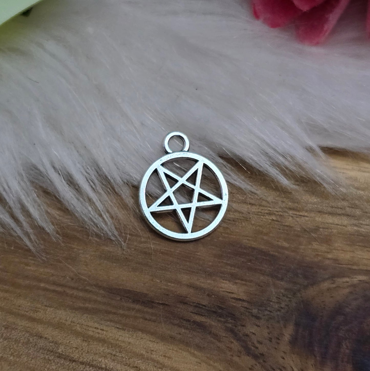 Auf dem Bild sind kleine Anhänger abgebildet, die die Form eines invertierten Pentagramms haben und in antik silberner Farbe gehalten sind. Jeder dieser Anhänger ist in einem Ring eingefasst und misst ungefähr 16 x 13 mm. Die Oberfläche der Anhänger weist eine feine Struktur auf und besitzt eine metallische Beschaffenheit, die das Licht reflektiert und ihnen einen attraktiven Glanz verleiht.