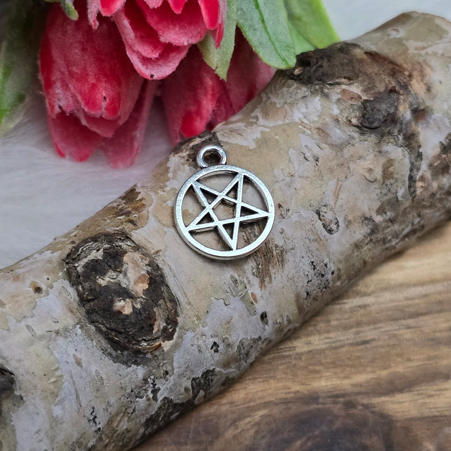 Auf dem Bild sind kleine Anhänger abgebildet, die die Form eines invertierten Pentagramms haben und in antik silberner Farbe gehalten sind. Jeder dieser Anhänger ist in einem Ring eingefasst und misst ungefähr 16 x 13 mm. Die Oberfläche der Anhänger weist eine feine Struktur auf und besitzt eine metallische Beschaffenheit, die das Licht reflektiert und ihnen einen attraktiven Glanz verleiht.