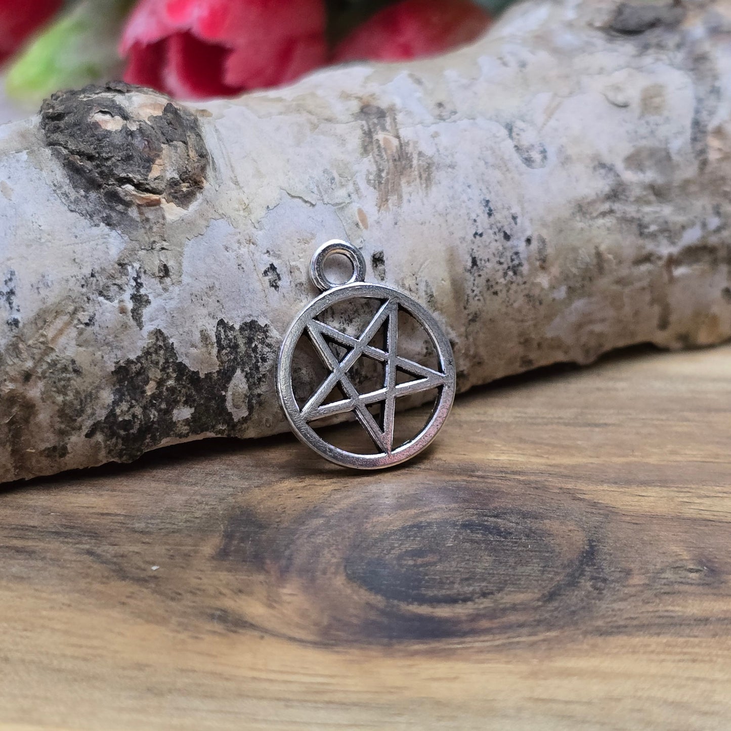 Auf dem Bild sind kleine Anhänger abgebildet, die die Form eines invertierten Pentagramms haben und in antik silberner Farbe gehalten sind. Jeder dieser Anhänger ist in einem Ring eingefasst und misst ungefähr 16 x 13 mm. Die Oberfläche der Anhänger weist eine feine Struktur auf und besitzt eine metallische Beschaffenheit, die das Licht reflektiert und ihnen einen attraktiven Glanz verleiht.