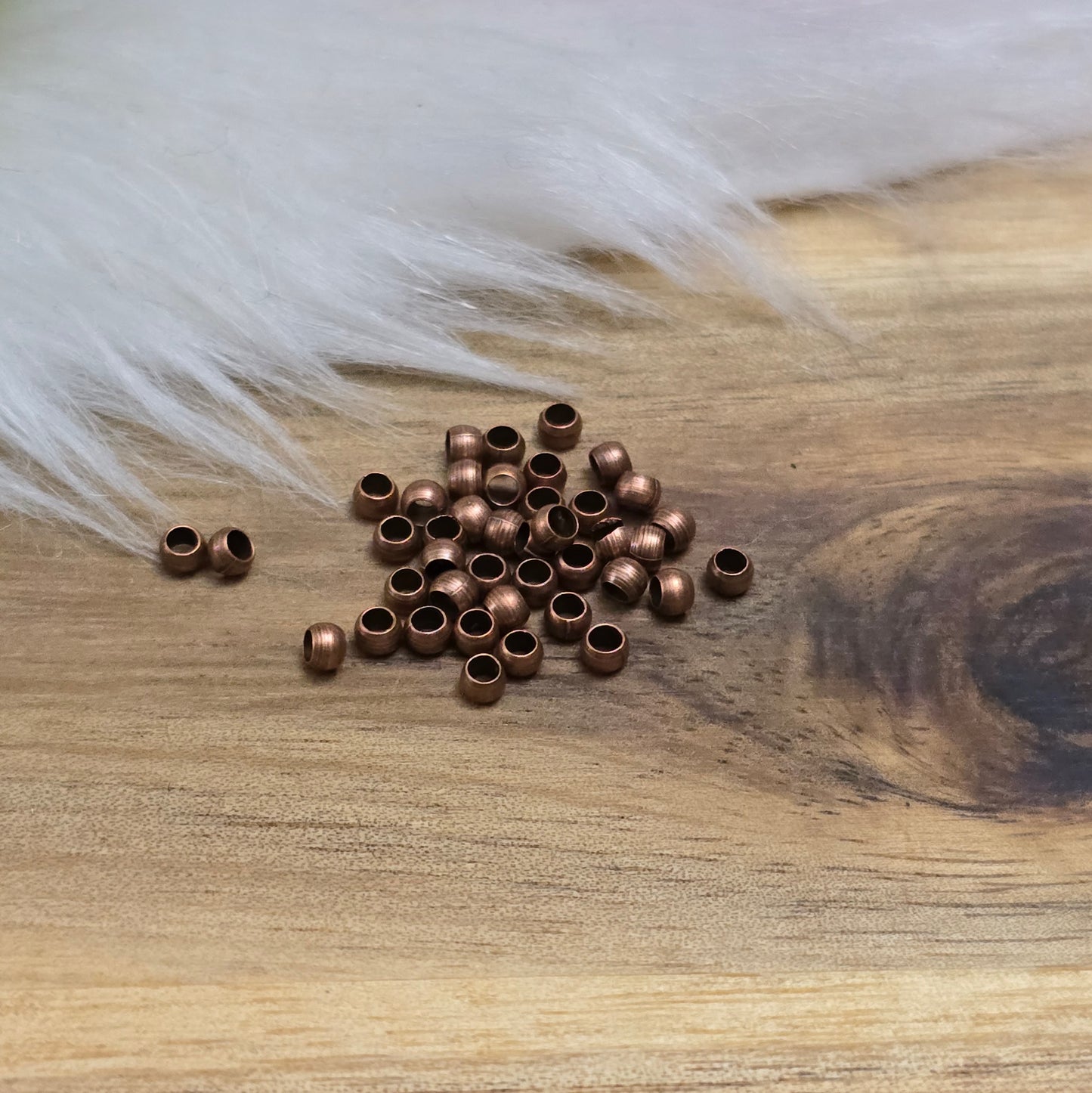 Das Bild zeigt Quetschperlen in Kugelform, antik kupferfarbig mit einem Durchmesser von 2,5mm. Ideal zum Fixieren von Perlen.