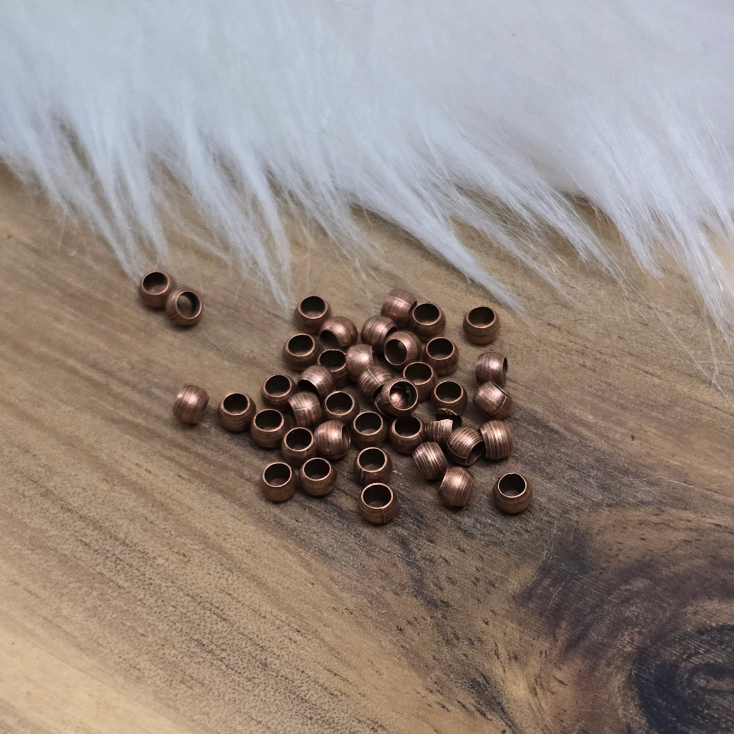 Das Bild zeigt Quetschperlen in Kugelform, antik kupferfarbig mit einem Durchmesser von 2,5mm. Ideal zum Fixieren von Perlen.