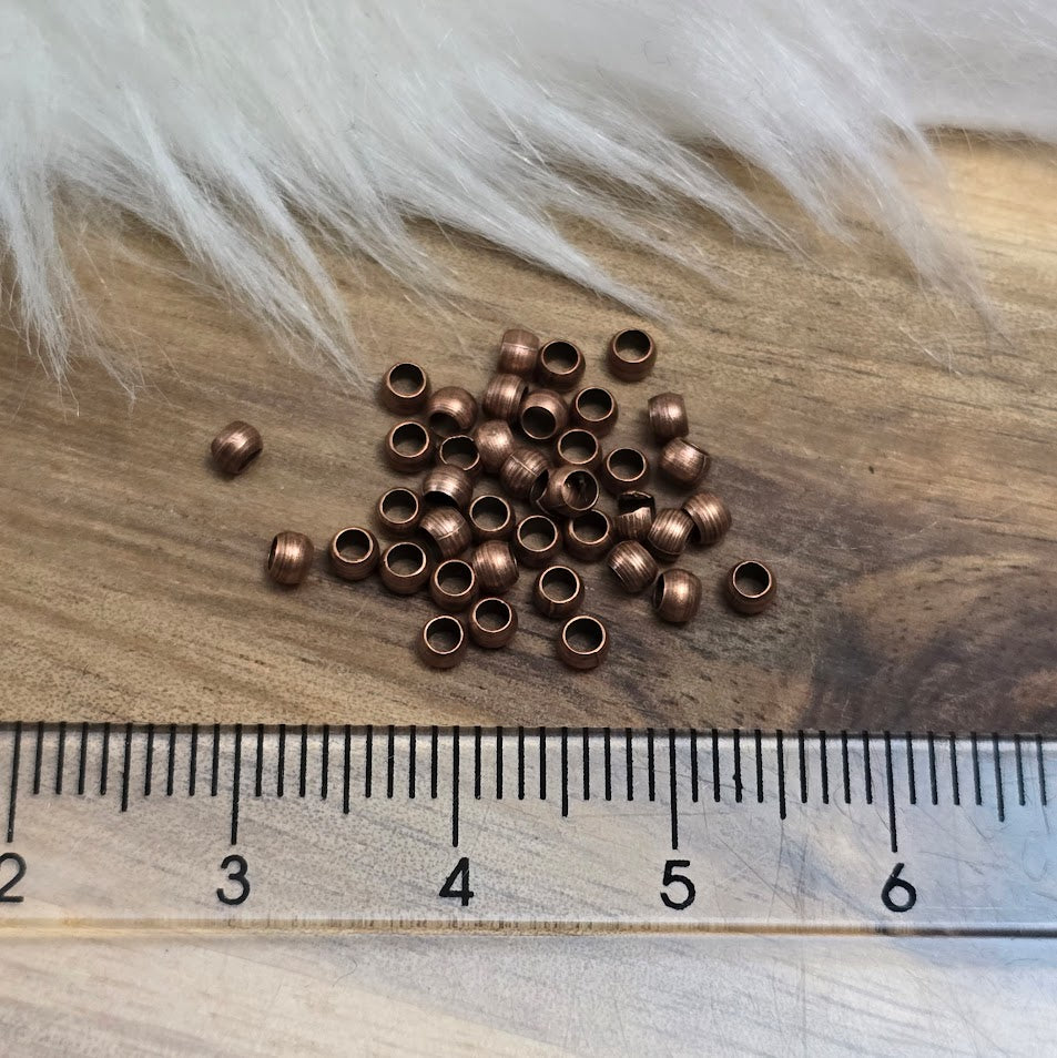 Das Bild zeigt Quetschperlen in Kugelform, antik kupferfarbig mit einem Durchmesser von 2,5mm. Ideal zum Fixieren von Perlen.