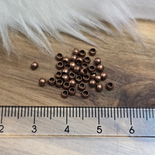 Das Bild zeigt Quetschperlen in Kugelform, antik kupferfarbig mit einem Durchmesser von 2,5mm. Ideal zum Fixieren von Perlen.