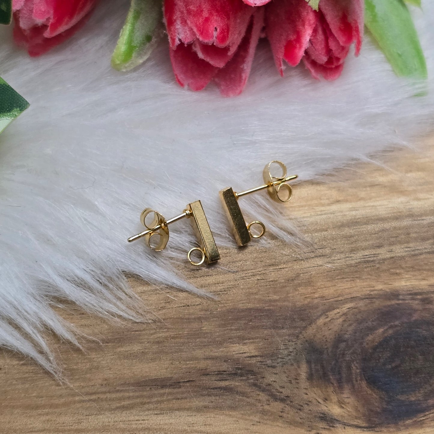 Das Bild zeigt goldfarbige Ohrstecker aus Edelstahl in Stäbchenform mit Öse & Flügelmuttern.
