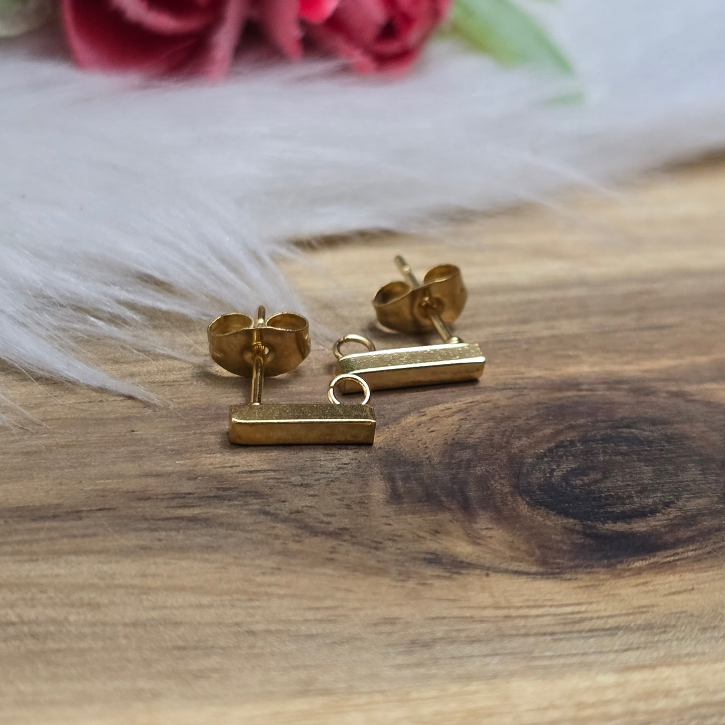 Das Bild zeigt goldfarbige Ohrstecker aus Edelstahl in Stäbchenform mit Öse & Flügelmuttern.