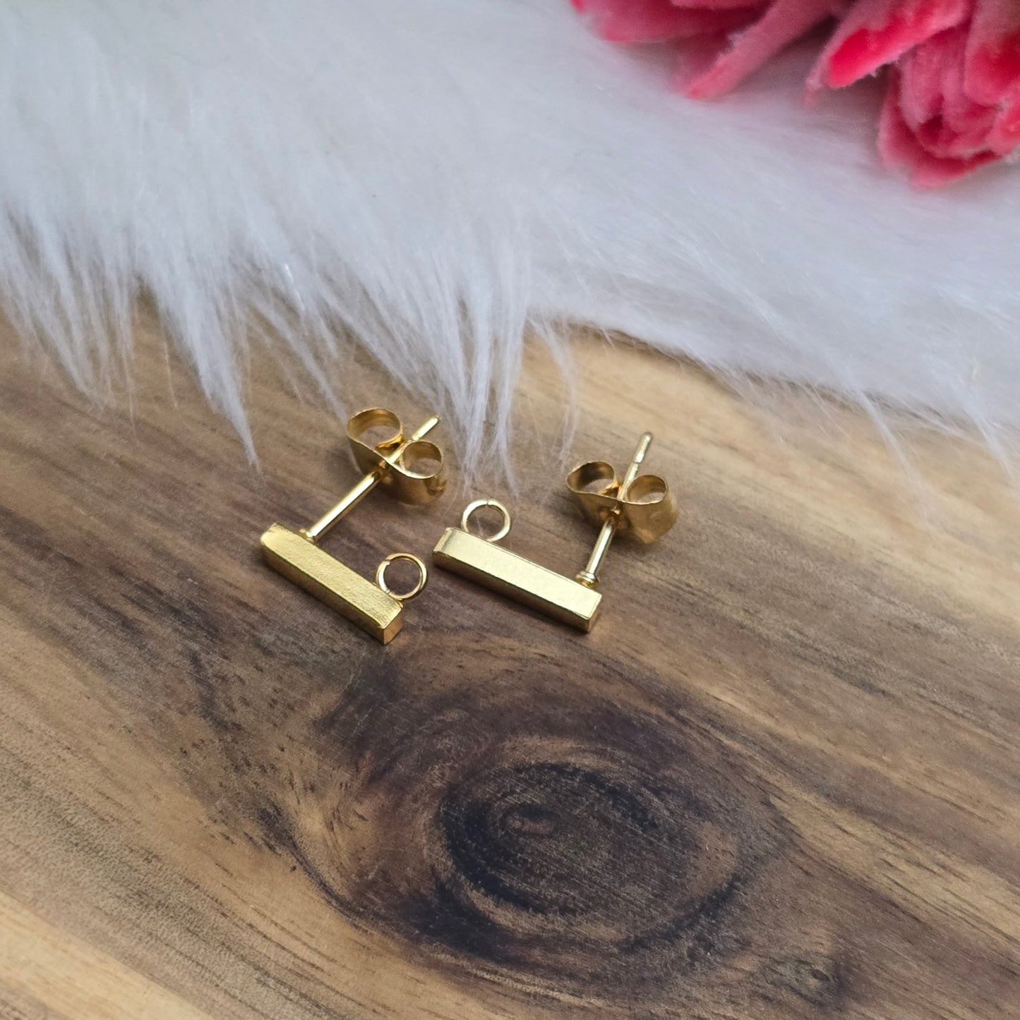 Das Bild zeigt goldfarbige Ohrstecker aus Edelstahl in Stäbchenform mit Öse & Flügelmuttern.