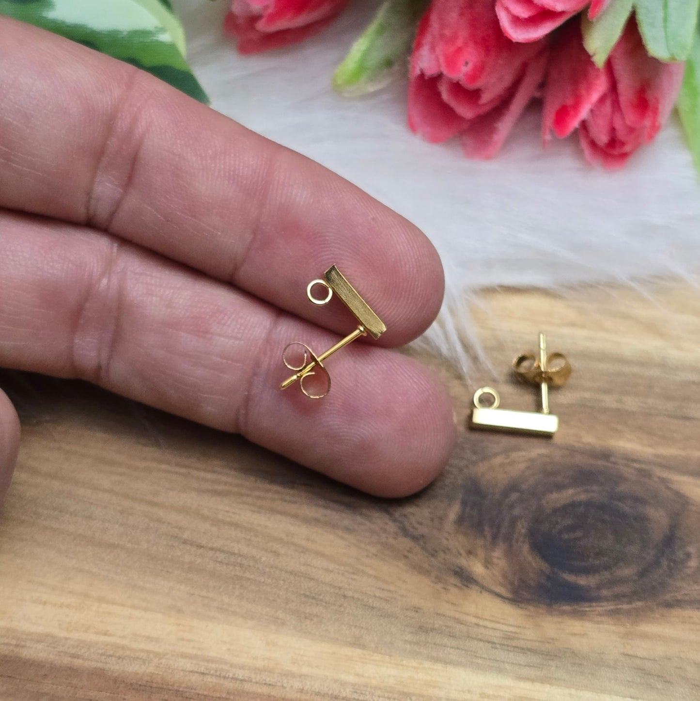Das Bild zeigt goldfarbige Ohrstecker aus Edelstahl in Stäbchenform mit Öse & Flügelmuttern.