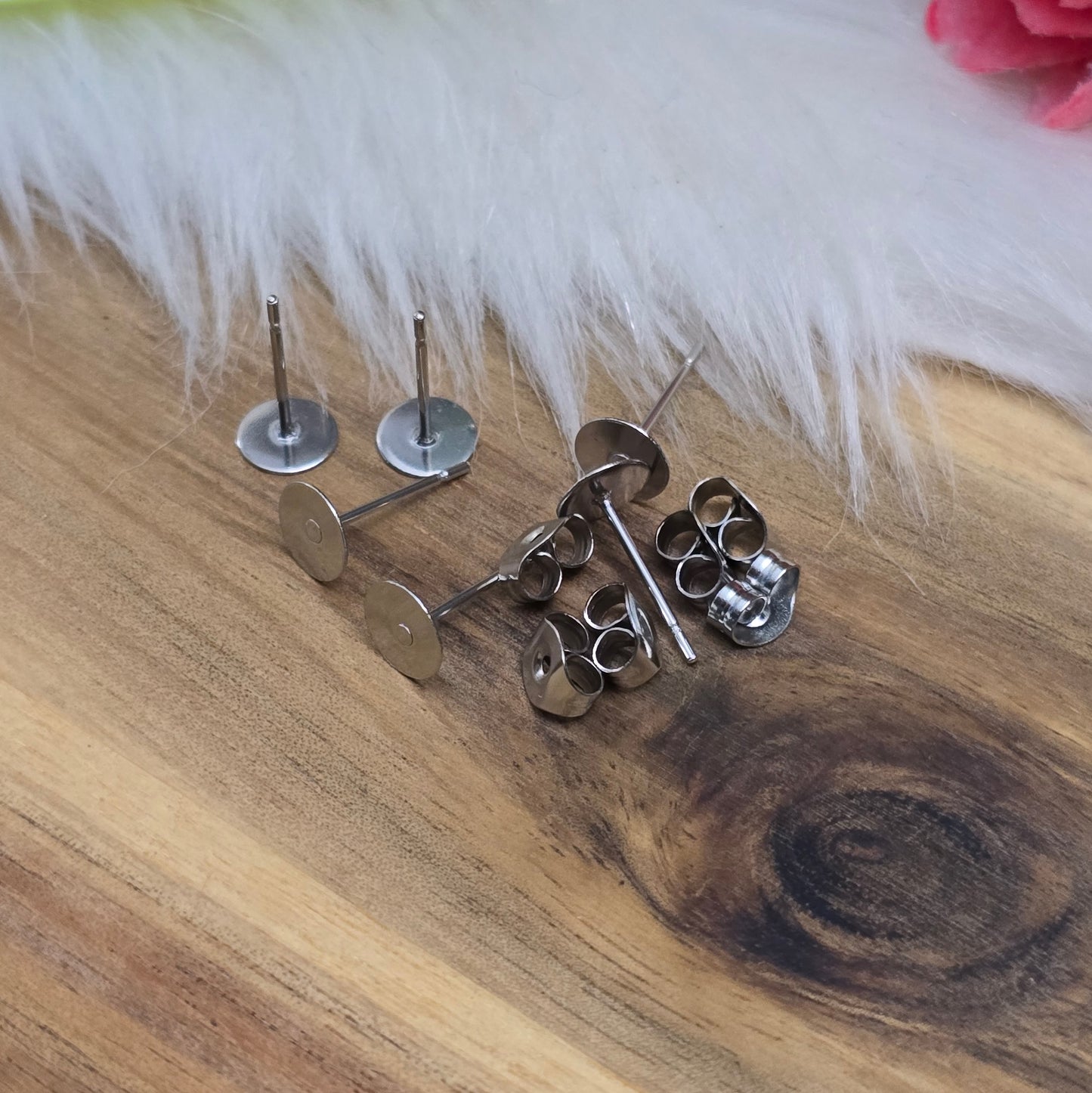 Das Bild zeigt Ohrstecker mit runder Klebeplatte aus Edelstahl in silber mit Flügelmuttern.