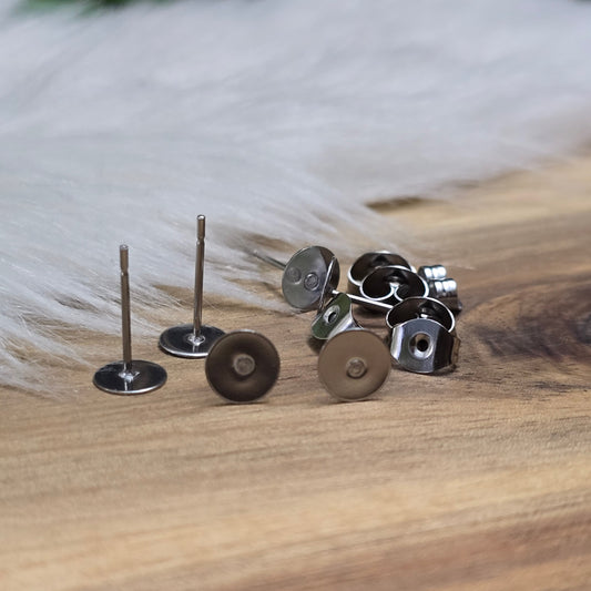 Das Bild zeigt Ohrstecker mit runder Klebeplatte aus Edelstahl in silber mit Flügelmuttern.