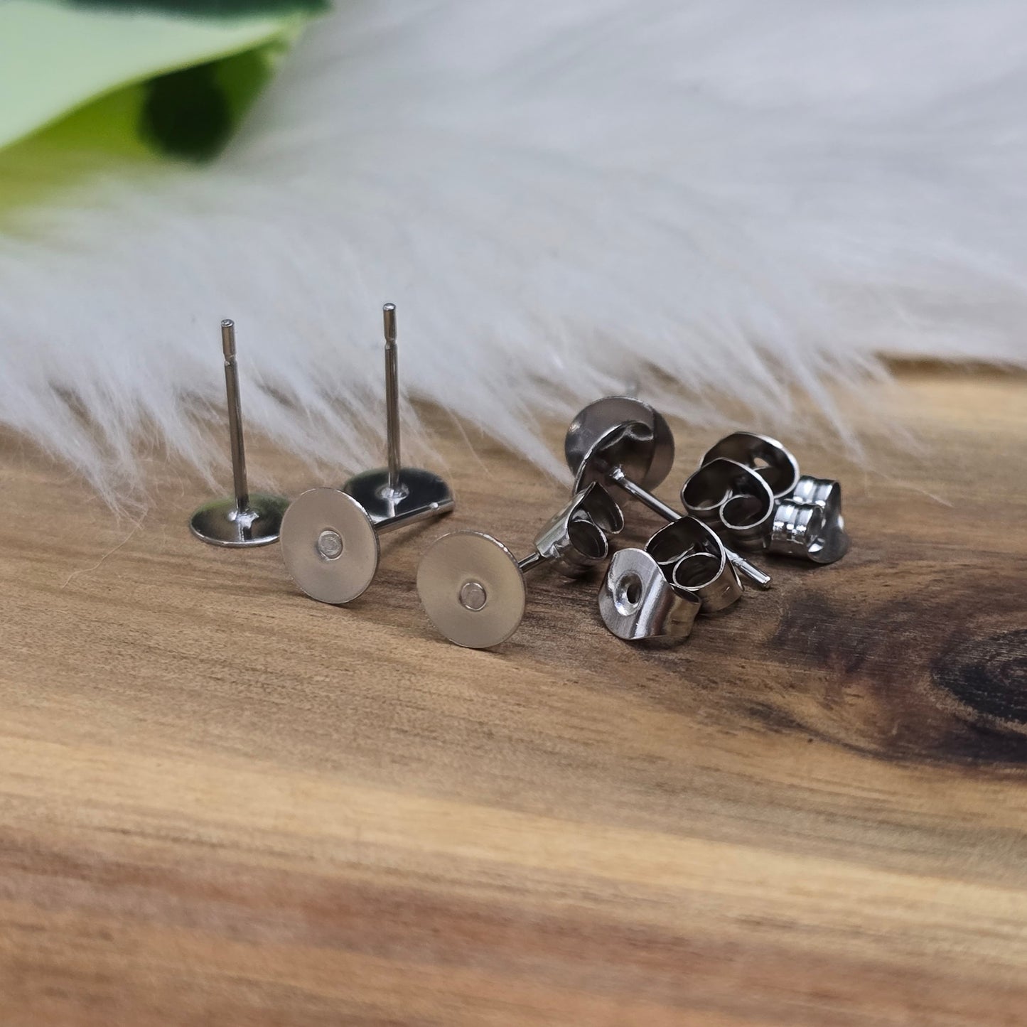 Das Bild zeigt Ohrstecker mit runder Klebeplatte aus Edelstahl in silber mit Flügelmuttern.