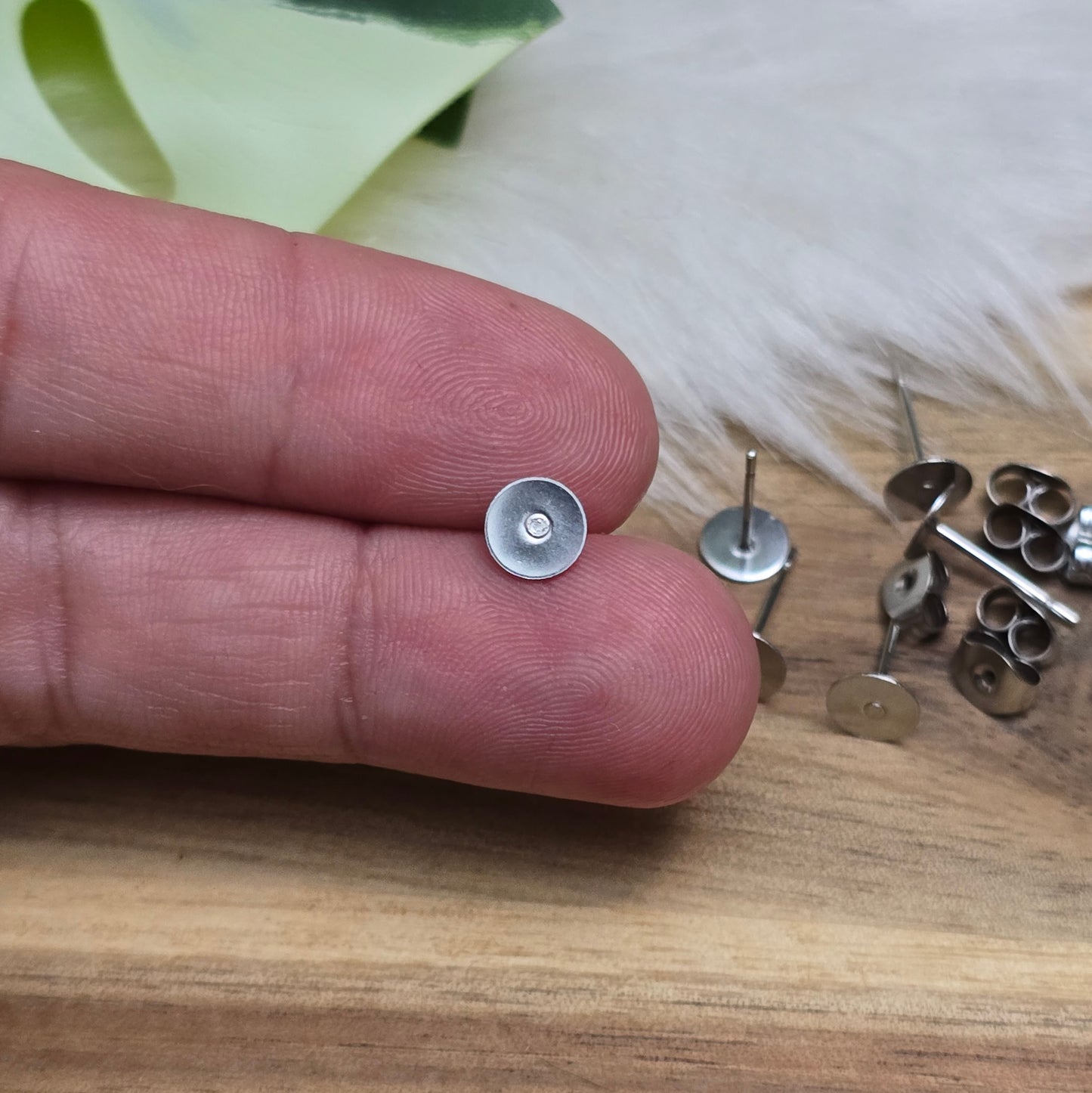 Das Bild zeigt Ohrstecker mit runder Klebeplatte aus Edelstahl in silber mit Flügelmuttern.