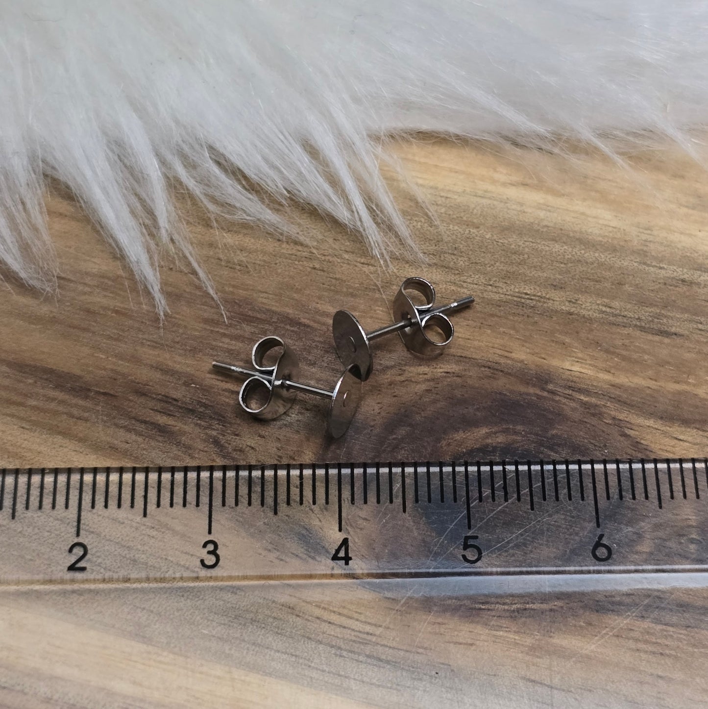 Das Bild zeigt Ohrstecker mit runder Klebeplatte aus Edelstahl in silber mit Flügelmuttern.
