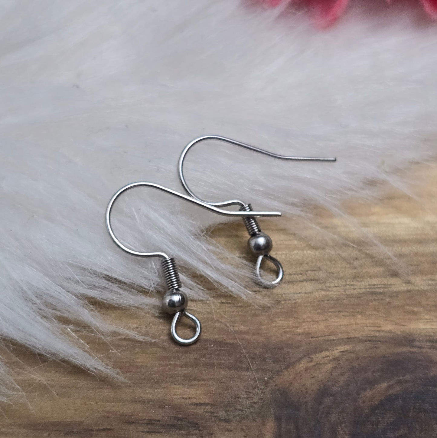 Das Bild zeigt ein Paar French Ohrhaken aus 304 Edelstahl in silberfarbener Optik. Die Haken haben eine geschwungene Form mit einer kleinen Kugel nahe der Öse, die zur Befestigung von Anhängern oder Perlen dient. Die Oberfläche ist glatt und glänzend, was ihnen ein edles und modernes Aussehen verleiht. Die stabilen Haken sind leicht gebogen, sodass sie bequem ins Ohr eingeführt werden können.