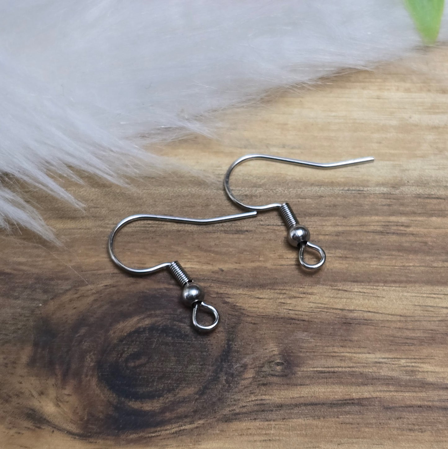 Das Bild zeigt ein Paar French Ohrhaken aus 304 Edelstahl in silberfarbener Optik. Die Haken haben eine geschwungene Form mit einer kleinen Kugel nahe der Öse, die zur Befestigung von Anhängern oder Perlen dient. Die Oberfläche ist glatt und glänzend, was ihnen ein edles und modernes Aussehen verleiht. Die stabilen Haken sind leicht gebogen, sodass sie bequem ins Ohr eingeführt werden können.