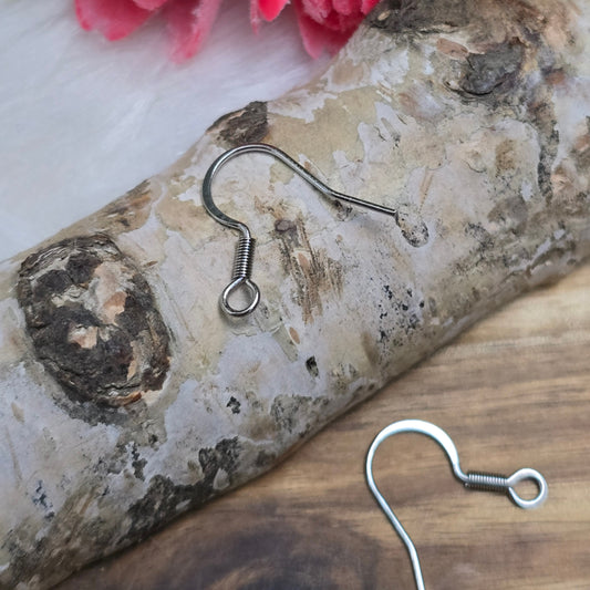 Das Bild zeigt ein Paar French Ohrhaken aus 304 Edelstahl in Silberfarbe. Die Haken haben eine elegante, geschwungene Form mit einer kleinen Öse am unteren Ende, die zur Befestigung von Anhängern oder Perlen dient. Die Oberfläche ist glatt und glänzend, was ihnen ein hochwertiges und modernes Aussehen verleiht. Mit einer Größe von etwa 16 mm sind sie ideal für die Gestaltung individueller Ohrringe.