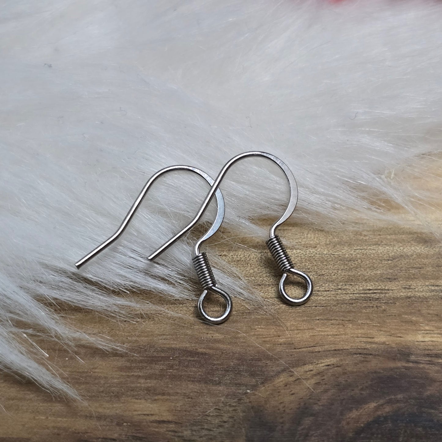 Das Bild zeigt ein Paar French Ohrhaken aus 304 Edelstahl in Silberfarbe. Die Haken haben eine elegante, geschwungene Form mit einer kleinen Öse am unteren Ende, die zur Befestigung von Anhängern oder Perlen dient. Die Oberfläche ist glatt und glänzend, was ihnen ein hochwertiges und modernes Aussehen verleiht. Mit einer Größe von etwa 16 mm sind sie ideal für die Gestaltung individueller Ohrringe.